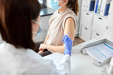 Image showing female doctor with syringe vaccinating patient