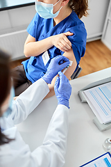 Image showing doctor with syringe vaccinating medical worker