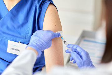 Image showing doctor with syringe vaccinating medical worker