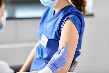 Image showing doctor with syringe vaccinating medical worker