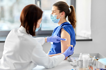 Image showing female doctor attaching patch to medical worker