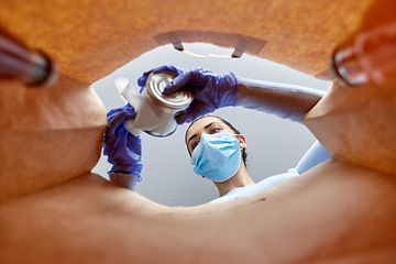 Image showing woman in gloves and mask disinfecting food