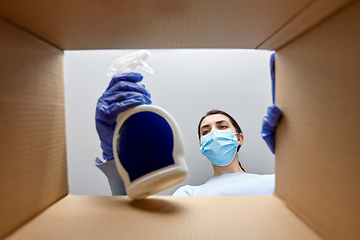 Image showing woman in mask taking cleaning supplies from box