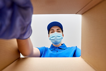 Image showing woman in mask looking inside cardboard parcel box