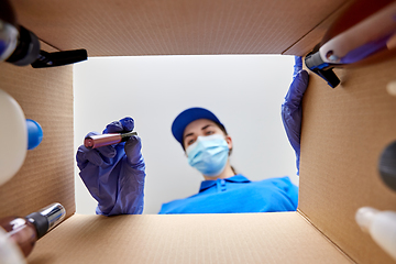 Image showing woman in mask packing parcel box with cosmetics