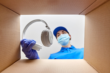 Image showing woman in mask packing headphones into parcel box