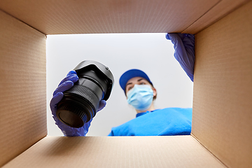 Image showing woman in mask packing camera into parcel box