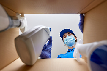 Image showing woman in mask packing cleaning supplies in box