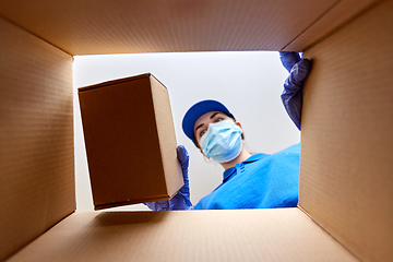 Image showing woman in mask packing box to parcel