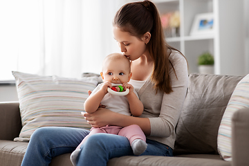 Image showing mother kissing baby with teething toy at home