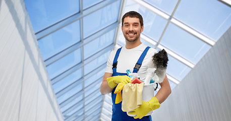 Image showing male cleaner with cleaning supplies in glasshouse