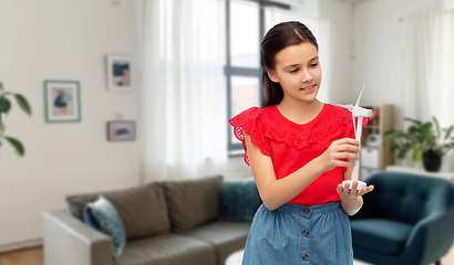 Image showing smiling girl with toy wind turbine at home