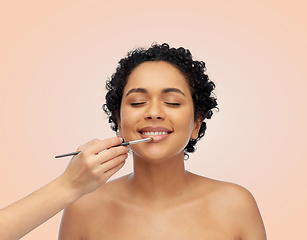 Image showing happy woman and hand of make up artist with brush