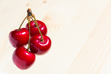 Image showing Four organic sweet cherries isolated on a wooden background