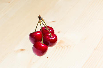 Image showing Four organic sweet cherries isolated on a wooden background