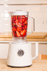 Image showing fresh strawberries in white Blender on a wooden table