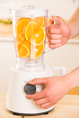 Image showing White blender with juicy oranges on a wooden table