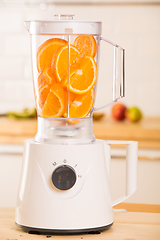 Image showing White blender with juicy oranges on a wooden table