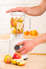 Image showing White blender with apples on a wooden table.