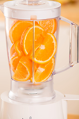 Image showing White blender with juicy oranges on a wooden table