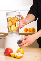 Image showing White blender with apples on a wooden table. 