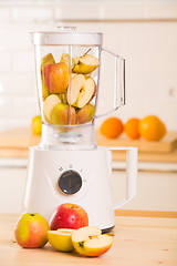 Image showing White blender with apples on a wooden table.