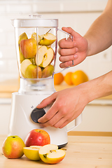 Image showing White blender with apples on a wooden table.