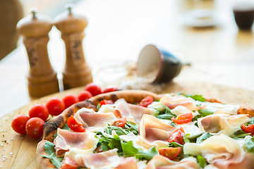 Image showing Pizza with cherry tomatoes, prosciutto and ruccola