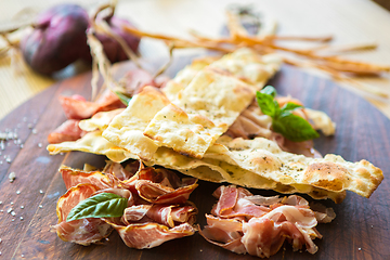 Image showing Homemade prosciutto and basil on a wooden board