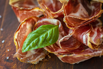 Image showing Homemade prosciutto and basil on a wooden board