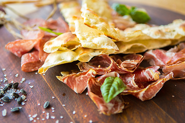Image showing Homemade prosciutto and basil on a wooden board