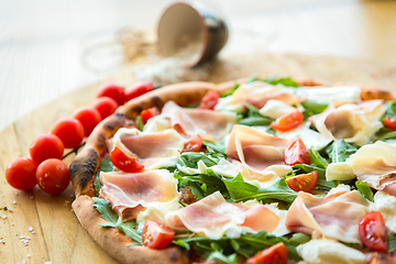 Image showing Pizza with cherry tomatoes, prosciutto and ruccola