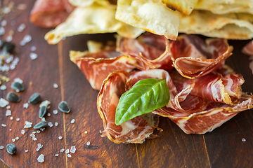 Image showing Homemade prosciutto and basil on a wooden board