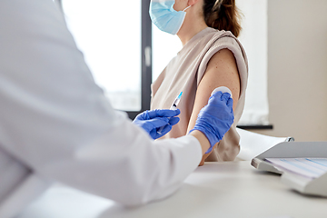 Image showing female doctor with syringe vaccinating patient