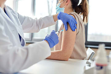 Image showing female doctor with syringe vaccinating patient