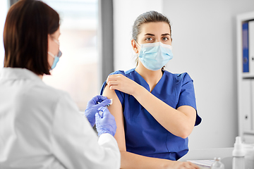 Image showing doctor with syringe vaccinating medical worker