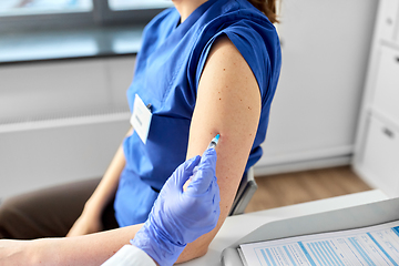 Image showing doctor with syringe vaccinating medical worker