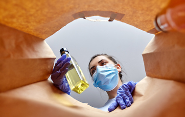 Image showing woman in gloves and mask with food in paper bag