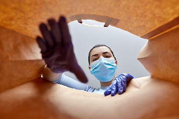 Image showing woman in gloves and mask with food in paper bag