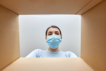 Image showing woman in mask looking inside cardboard parcel box