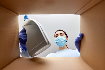 Image showing woman in mask taking cleaning supplies from box