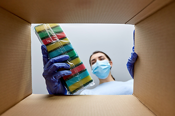 Image showing woman in mask taking cleaning supplies from box