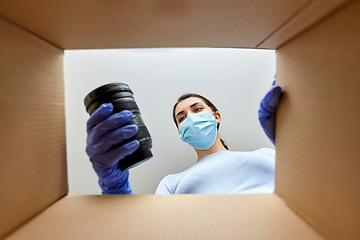 Image showing woman in mask packing camera into parcel box