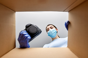 Image showing woman in mask packing camera into parcel box