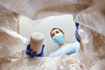 Image showing woman in mask packing candles into parcel box