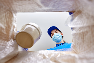 Image showing woman in mask packing flower pot to parcel box