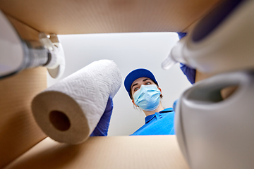 Image showing woman in mask packing cleaning supplies in box