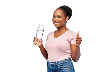 Image showing happy african woman drinks water from glass bottle