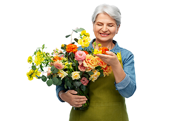 Image showing smiling senior woman in garden apron with flowers