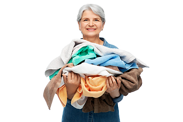 Image showing smiling senior woman with heap of bath towels